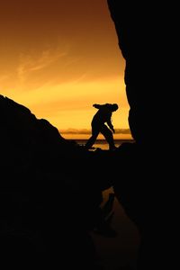 Silhouette man standing on mountain against sky during sunset