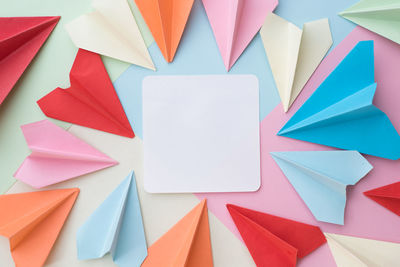 Directly above shot of blank paper with colorful origami airplanes on table