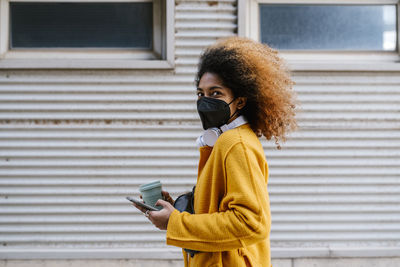 Portrait of young woman using mobile phone while standing outdoors