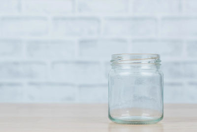 Close-up of glass jar on table against wall