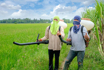 Portrait of farmers gesturing thumbs up while working on agricultural field