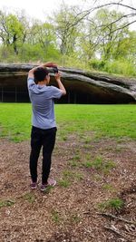 Full length of man photographing on field