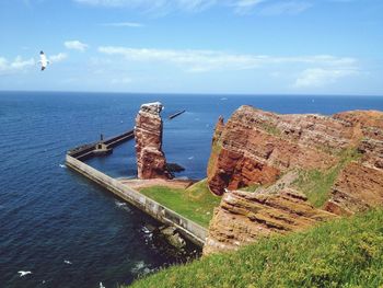 High angle view of rock formations by sea against sky