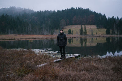 Man standing against lake and trees