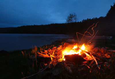 Bonfire on wooden log against sky at night