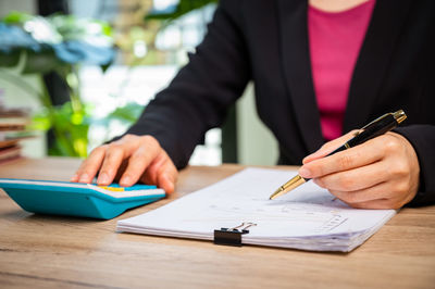 Midsection of man holding paper on table