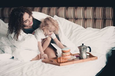 Young woman using mobile phone on bed at home