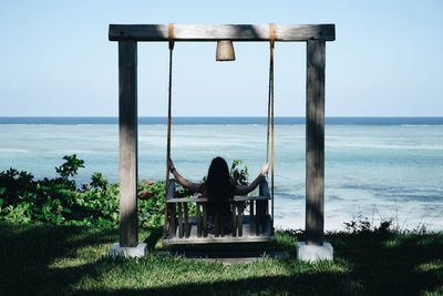 Woman sitting on swing at beach