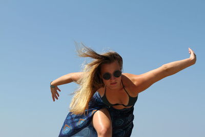 Young woman standing at beach against clear sky