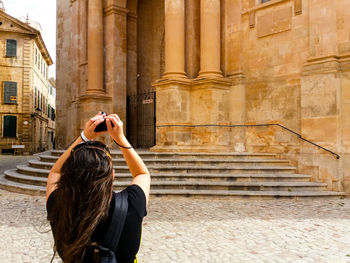 Full length of woman photographing at temple