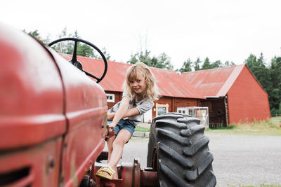 Girl sat on a tractor smiling whilst at a farm in sweden