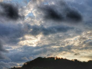 Low angle view of silhouette trees against dramatic sky