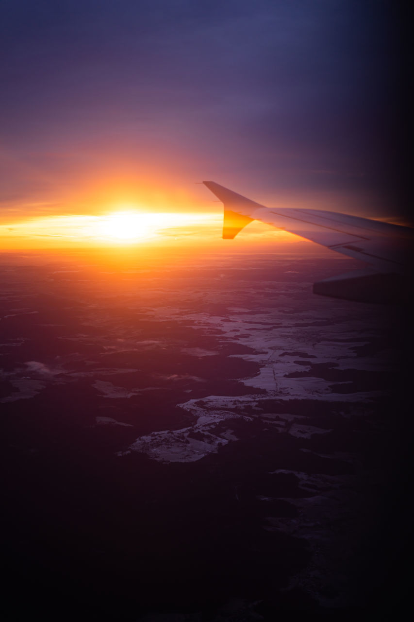 AIRPLANE FLYING OVER SEA DURING SUNSET