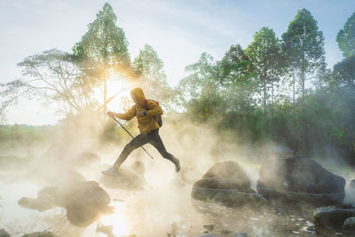 Full length of man jumping on rock against trees