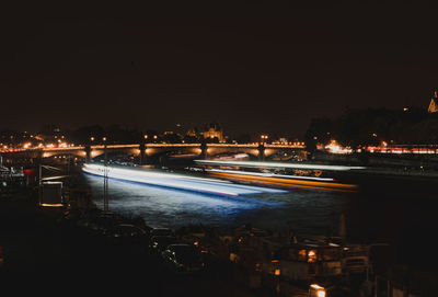 High angle view of illuminated city by river against sky at night