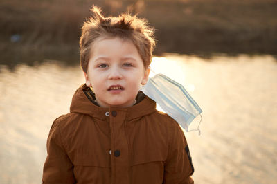 Portrait of boy standing against water