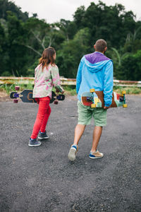 Rear view of siblings playing on the road