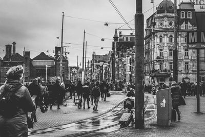 People walking on city street against sky, black and white