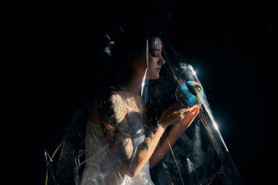 Woman looking at illuminated lighting equipment against black background