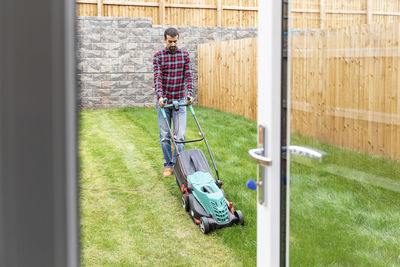 Man mowing lawn with push lawn mower at backyard