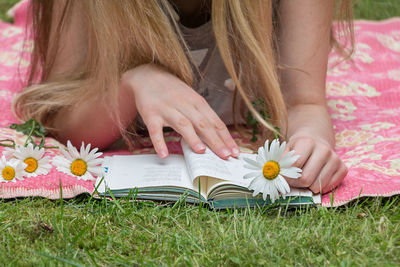 Midsection of woman reading book on field