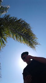 Low angle view of man with palm tree against clear sky