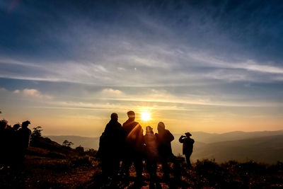 Silhouette people standing on land against sky during sunset