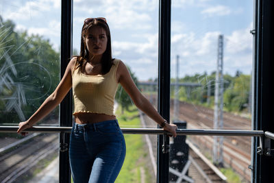 Woman standing by railing against window