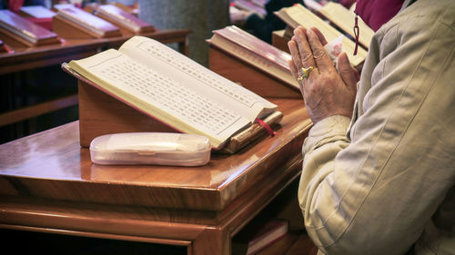 Midsection of man reading prayer book at desk