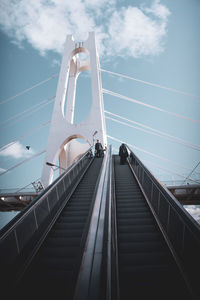 Low angle view of people on bridge against sky