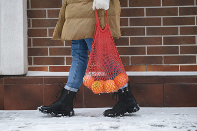 Happy woman carry reusable bag with oranges from the shop. walking outdoors in winter. festive