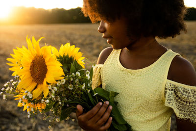 Midsection of woman holding yellow flowering plant