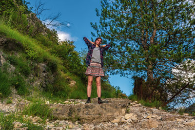 Woman standing by tree against sky