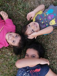 Portrait of smiling siblings lying on grassy land