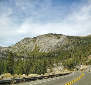 Road by trees against sky