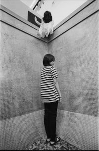 Rear view of boy standing against wall