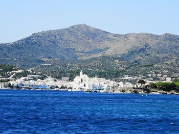 Scenic view of sea and buildings against clear blue sky