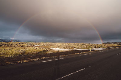 Rainbow over road against sky