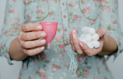 Midsection of woman holding tampon with menstrual cup