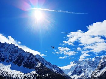 Low angle view of snowcapped mountains against blue sky