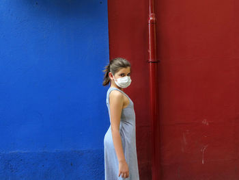 Woman standing against blue wall