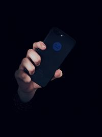 Close-up of person using mobile phone against black background