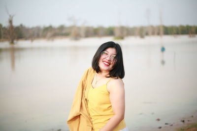 Portrait of smiling young woman standing in water