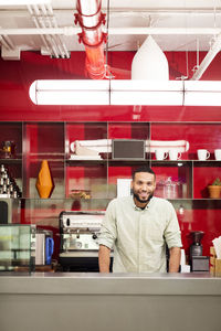 Portrait of smiling businessman standing at office kitchen