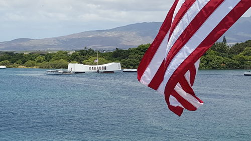 Scenic view of flag by lake against sky