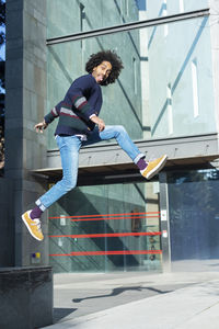 Full length of man jumping over footpath in city