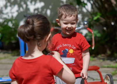 Siblings are playing with soap bubbles in the backyard on a sunny day