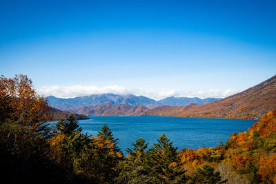 Scenic view of lake chuzenji and mountains against blue sky