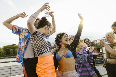 Carefree multiracial non-binary friends dancing with each other in city