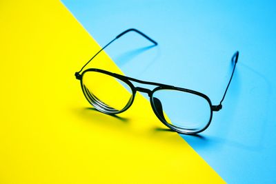 High angle view of eyeglasses on table against yellow background